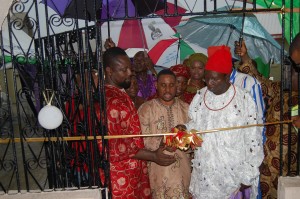 Rev. (Dr.) J.A. Ottuh cutting the tape to commission the hotel and assisted by Mr. Fred Atsiangbe (Left) and Chief Patrick Ogiba (Right)